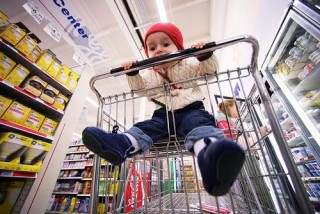 A young child playfully licking a shopping cart handle.